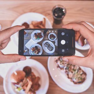 Foto de un comensal tomando una foto de su comida en un restaurante